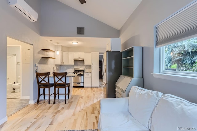 living room featuring a wall mounted AC, high vaulted ceiling, light hardwood / wood-style flooring, and sink