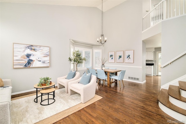 living area featuring dark wood-type flooring, high vaulted ceiling, and a chandelier