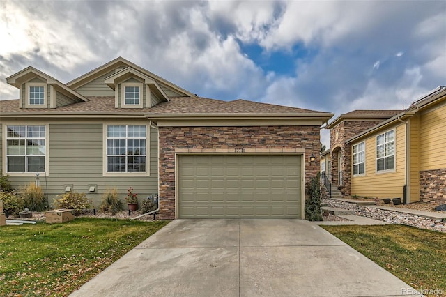 view of front of property with a garage, a shingled roof, concrete driveway, stone siding, and a front yard