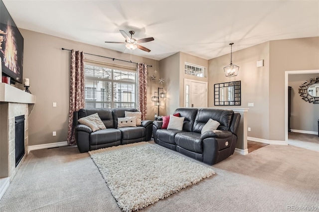 carpeted living room featuring ceiling fan with notable chandelier, a fireplace, and baseboards