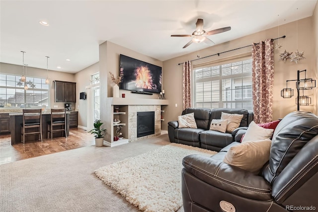 living area featuring baseboards, a ceiling fan, light colored carpet, a tiled fireplace, and recessed lighting