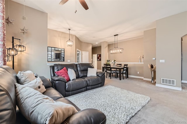 living room with visible vents, light carpet, baseboards, and ceiling fan with notable chandelier