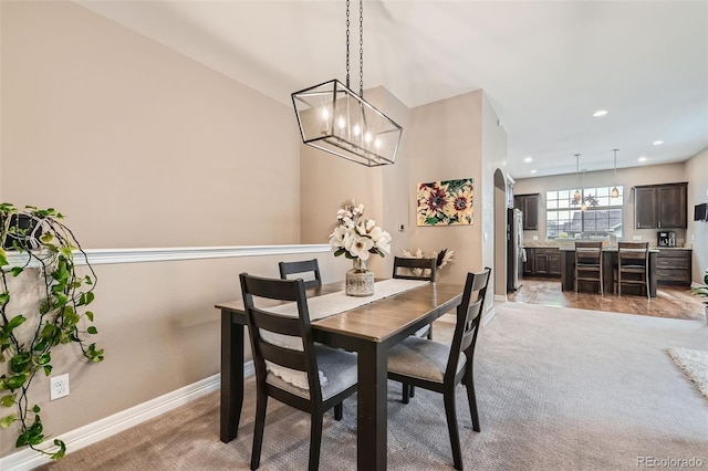 dining room featuring baseboards, arched walkways, light colored carpet, an inviting chandelier, and recessed lighting