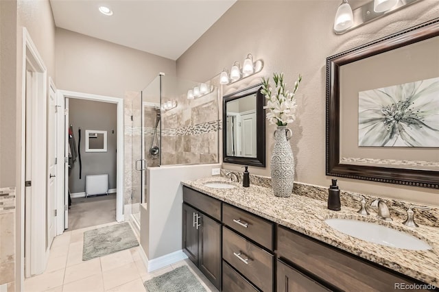 bathroom featuring tile patterned floors, a sink, a shower stall, and double vanity