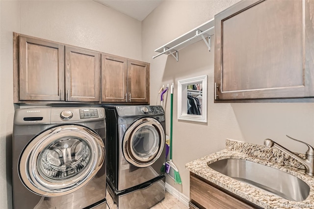 laundry room featuring washing machine and clothes dryer, a sink, cabinet space, and baseboards