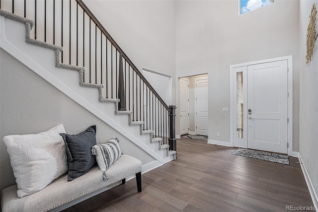 foyer entrance featuring baseboards, stairs, a towering ceiling, and wood finished floors