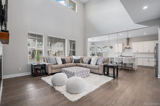 living area featuring a towering ceiling, visible vents, baseboards, dark wood-style floors, and recessed lighting