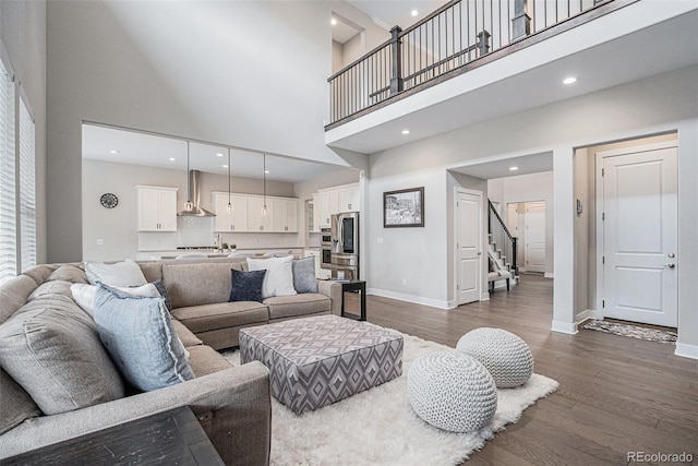 living area featuring stairs, a towering ceiling, baseboards, recessed lighting, and dark wood finished floors
