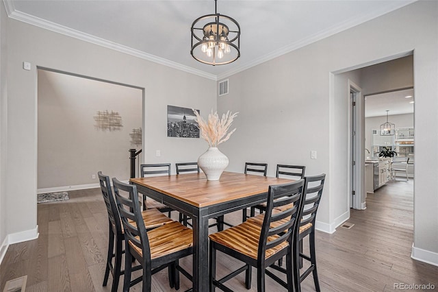 dining room featuring visible vents, ornamental molding, dark wood-type flooring, and a chandelier