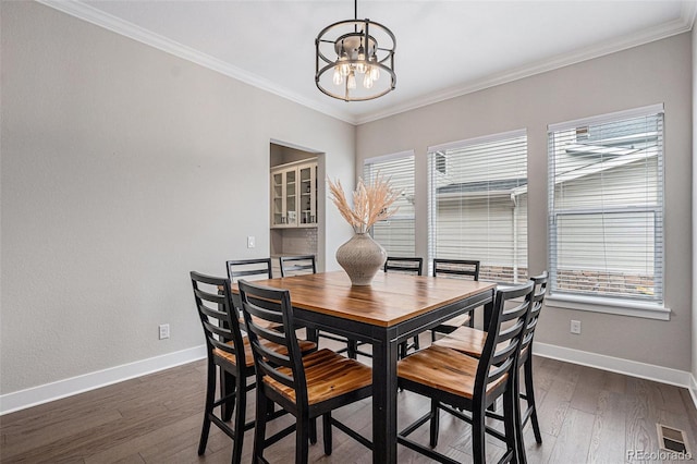 dining space featuring an inviting chandelier, baseboards, crown molding, and dark wood finished floors