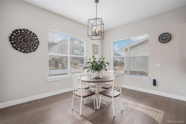 dining area with visible vents, baseboards, dark wood-type flooring, and an inviting chandelier