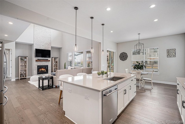 kitchen with wood finished floors, baseboards, a sink, and dishwasher