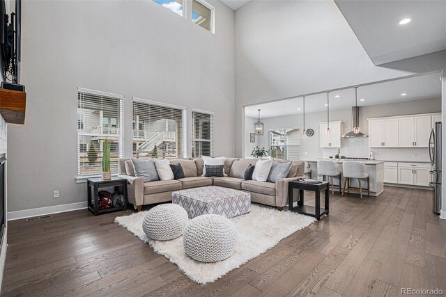 6733 S Waterloo Ct, Aurora, CO 80016 - living room featuring dark wood-style floors, baseboards, a towering ceiling, and recessed lighting