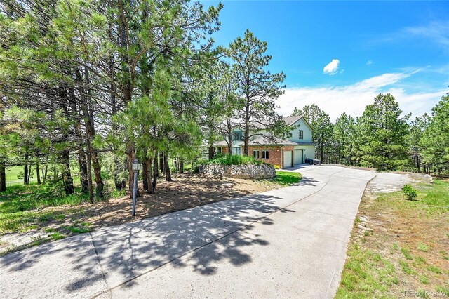 6681 Flintwood Rd, Parker, CO 80138 - view of property hidden behind natural elements featuring driveway, a garage, and brick siding