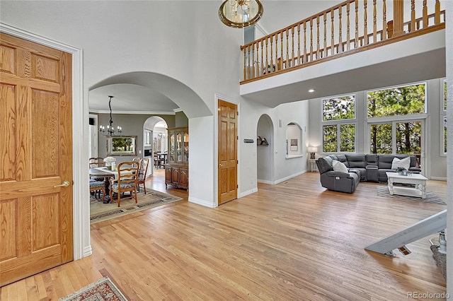 6681 Flintwood Rd, Parker, CO 80138 - living area with a chandelier, arched walkways, light wood finished floors, a high ceiling, and healthy amount of natural light