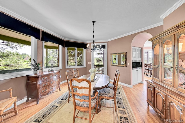 6681 Flintwood Rd, Parker, CO 80138 - dining area with arched walkways, light wood finished floors, a chandelier, and ornamental molding