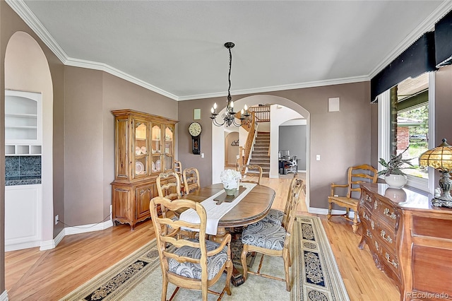 6681 Flintwood Rd, Parker, CO 80138 - dining area featuring arched walkways, light wood-type flooring, a chandelier, ornamental molding, and stairs