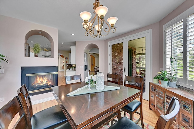 6681 Flintwood Rd, Parker, CO 80138 - dining area featuring light wood-style flooring, healthy amount of natural light, arched walkways, a multi sided fireplace, and recessed lighting