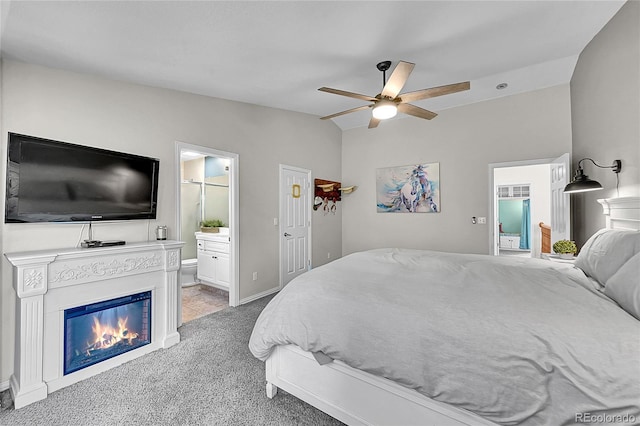 6681 Flintwood Rd, Parker, CO 80138 - carpeted bedroom featuring vaulted ceiling, connected bathroom, ceiling fan, and a glass covered fireplace