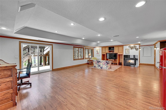 6681 Flintwood Rd, Parker, CO 80138 - living room featuring a tray ceiling, a fireplace, a textured ceiling, light wood-style floors, and recessed lighting