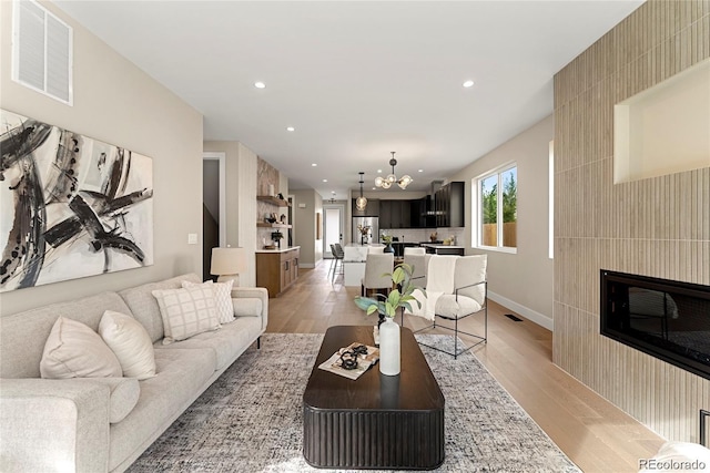 living room with a notable chandelier, visible vents, recessed lighting, and light wood finished floors