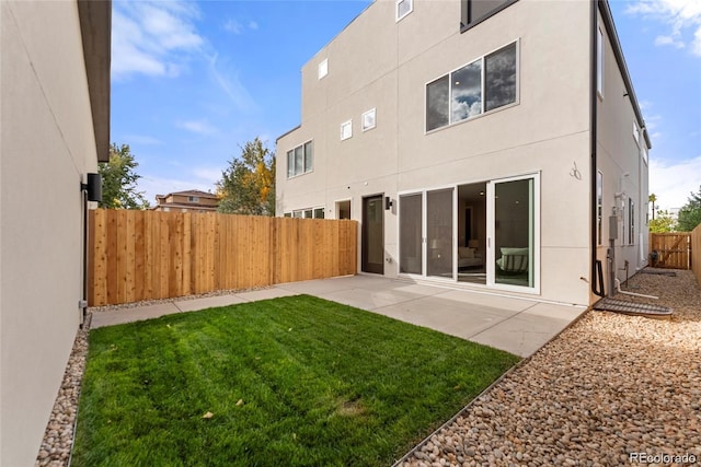 rear view of house with stucco siding, a patio, a lawn, and a fenced backyard