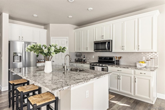 kitchen with white cabinetry, stainless steel appliances, and a center island with sink