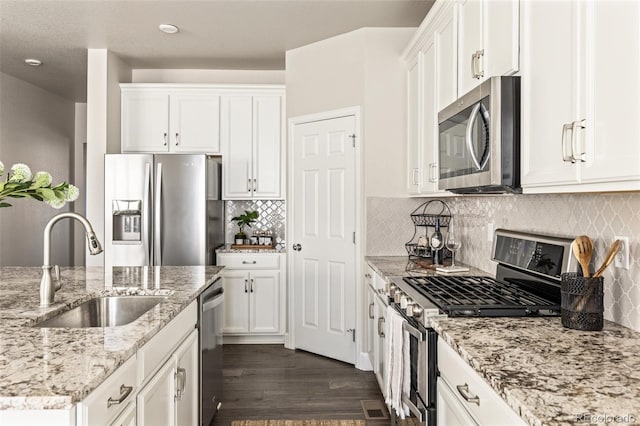 kitchen with light stone counters, appliances with stainless steel finishes, sink, and white cabinets