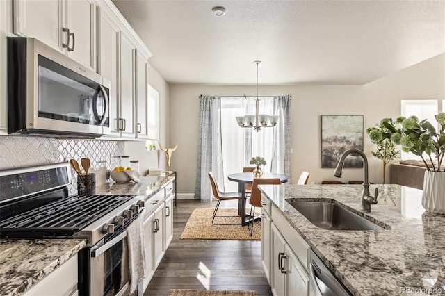 kitchen featuring dark hardwood / wood-style floors, pendant lighting, white cabinetry, sink, and stainless steel appliances