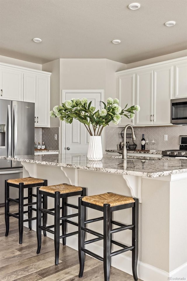 kitchen featuring appliances with stainless steel finishes, light stone countertops, and white cabinets