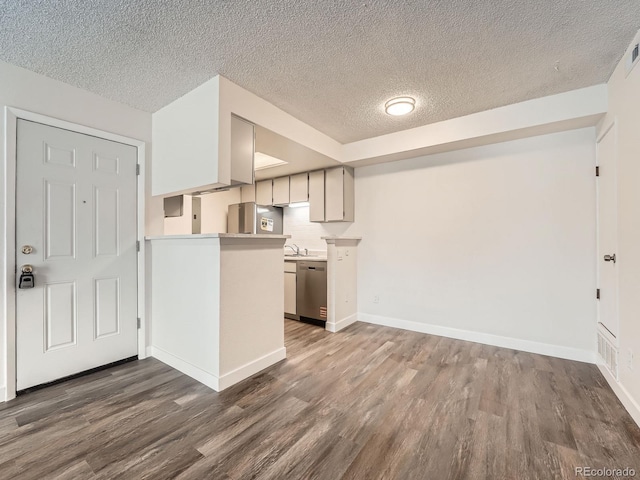 kitchen featuring stainless steel appliances, light countertops, dark wood finished floors, and baseboards