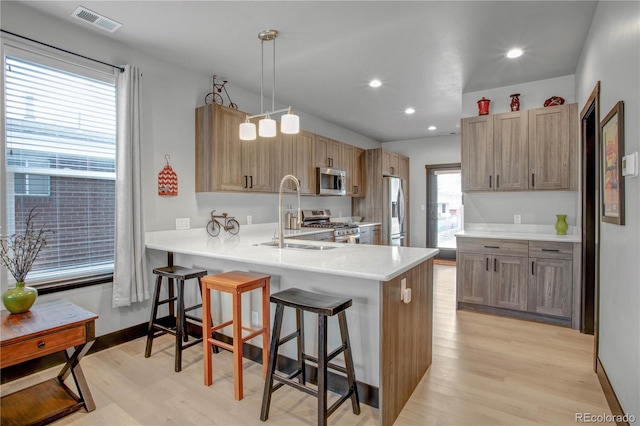 1111 E St, Salida, CO 81201 - kitchen featuring appliances with stainless steel finishes, light wood finished floors, a kitchen bar, a peninsula, and light countertops