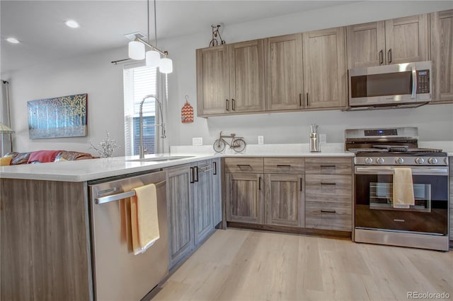 1111 E St, Salida, CO 81201 - kitchen featuring stainless steel appliances, light wood-type flooring, a peninsula, light countertops, and hanging light fixtures