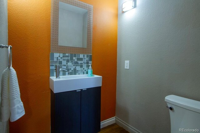 bathroom with backsplash, vanity, wood-type flooring, and toilet