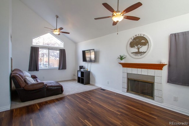 unfurnished living room with a tiled fireplace, a ceiling fan, wood finished floors, high vaulted ceiling, and baseboards