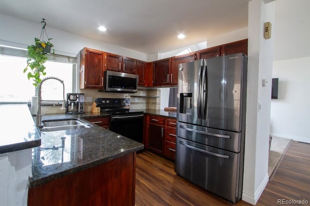 kitchen with stainless steel appliances, dark wood finished floors, a sink, and dark brown cabinets