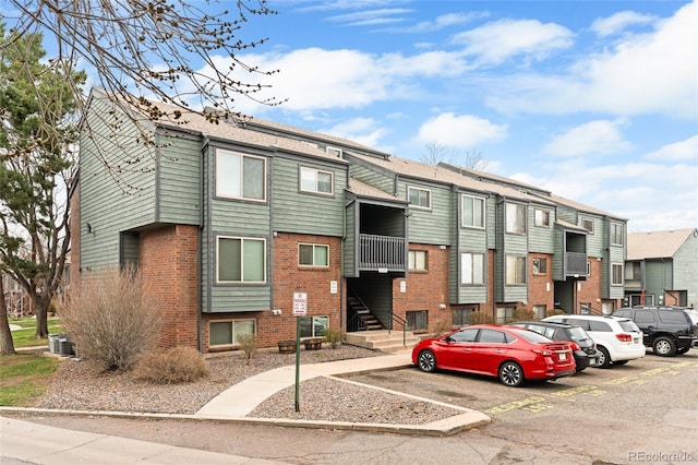 view of property featuring uncovered parking, cooling unit, and a residential view