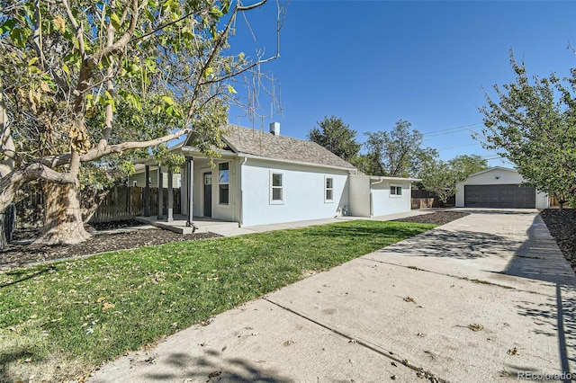 view of front of home featuring a garage, an outbuilding, and a front lawn