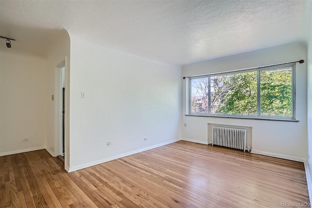 85 N Grant St Unit 22, Denver, CO 80203 - unfurnished room with radiator, light wood-type flooring, a textured ceiling, and baseboards