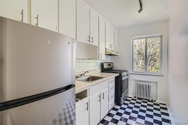 kitchen with appliances with stainless steel finishes, radiator heating unit, sink, and white cabinetry