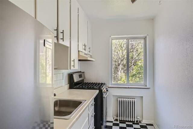 85 N Grant St Unit 22, Denver, CO 80203 - kitchen with freestanding refrigerator, radiator heating unit, stainless steel gas stove, under cabinet range hood, and a sink