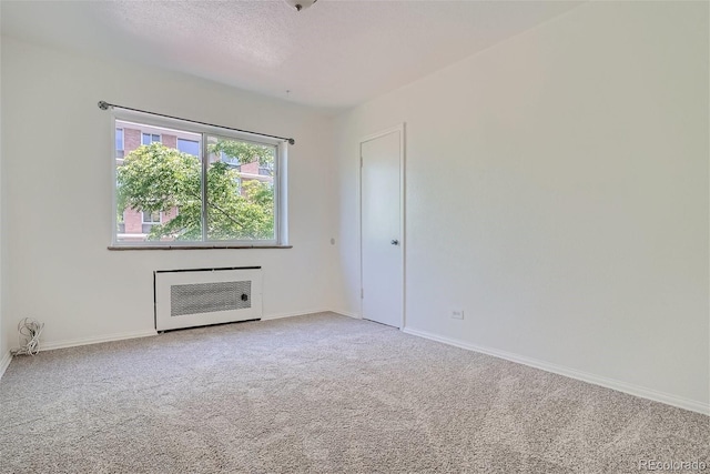 empty room with a textured ceiling, heating unit, and carpet floors