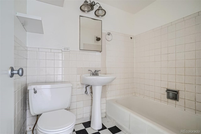 bathroom featuring toilet, tile walls, and sink