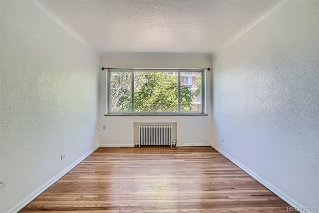 spare room with radiator and light hardwood / wood-style floors