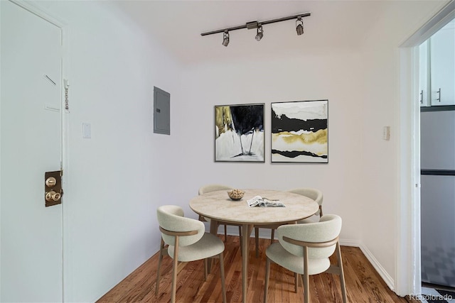 dining room featuring electric panel, track lighting, and hardwood / wood-style flooring