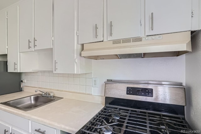 kitchen featuring stainless steel range with gas stovetop, backsplash, white cabinetry, and sink