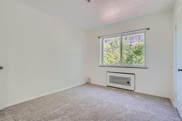 carpeted empty room with a textured ceiling and heating unit