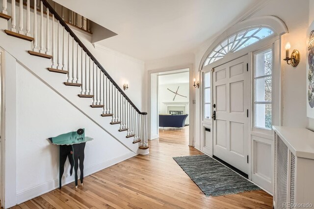 foyer with stairway, baseboards, light wood-style flooring, and crown molding