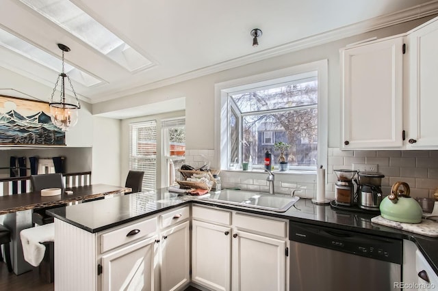 kitchen with dark countertops, dishwasher, crown molding, and a sink