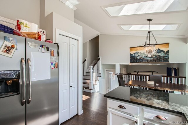 kitchen with dark wood finished floors, vaulted ceiling with skylight, stainless steel refrigerator with ice dispenser, hanging light fixtures, and white cabinets